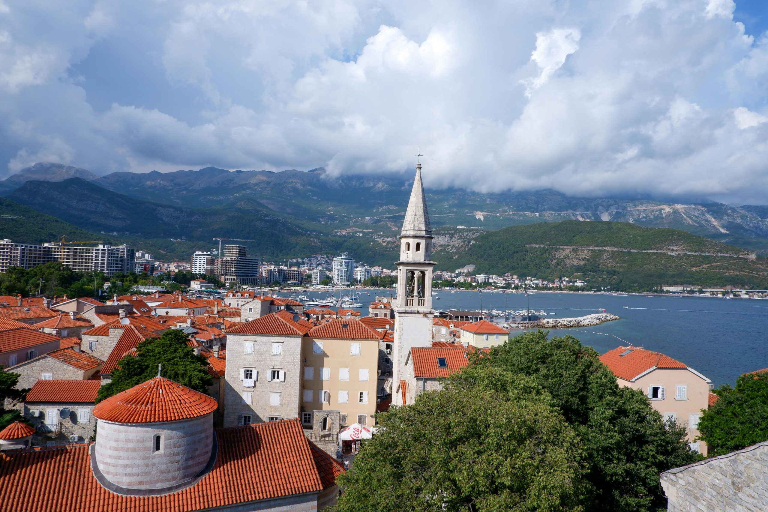 Scenic aerial view of coastal town with red roofs and mountains.