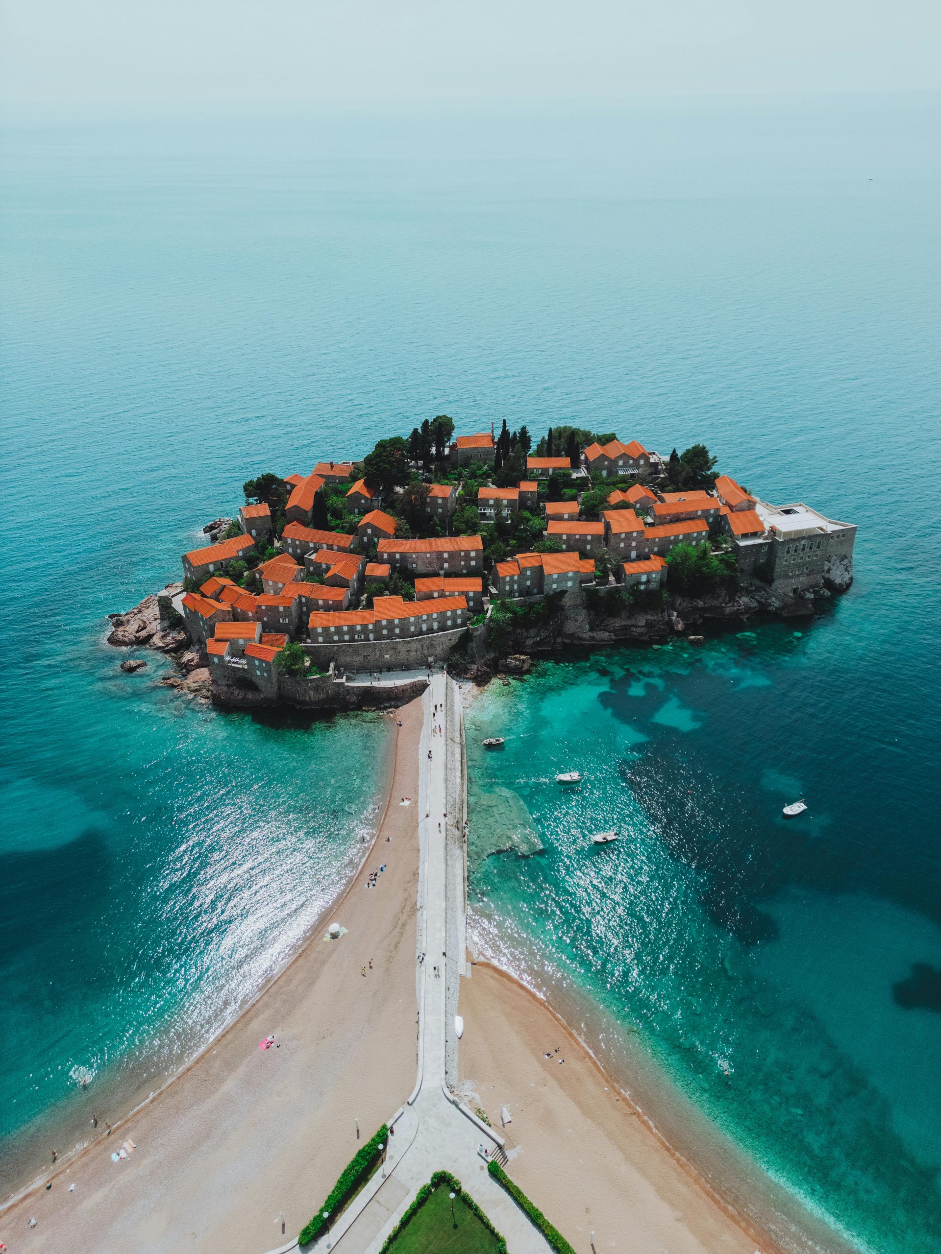 Stunning aerial view of Sveti Stefan island in Montenegro with turquoise seas and red-roofed buildings.